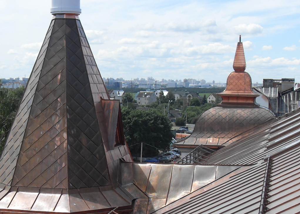 Hand-formed copper turrets with diamond-pattern shingles overlooking a cityscape